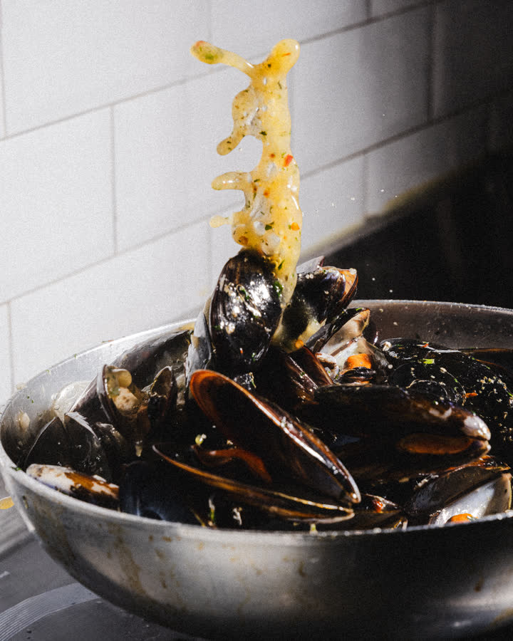 cozze in padella e spaghetti sollevati con la forchetta